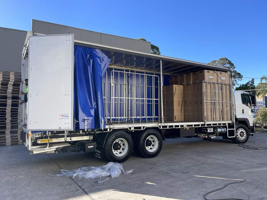 Quickcargo curtain-side truck loaded with cartons secured for transit